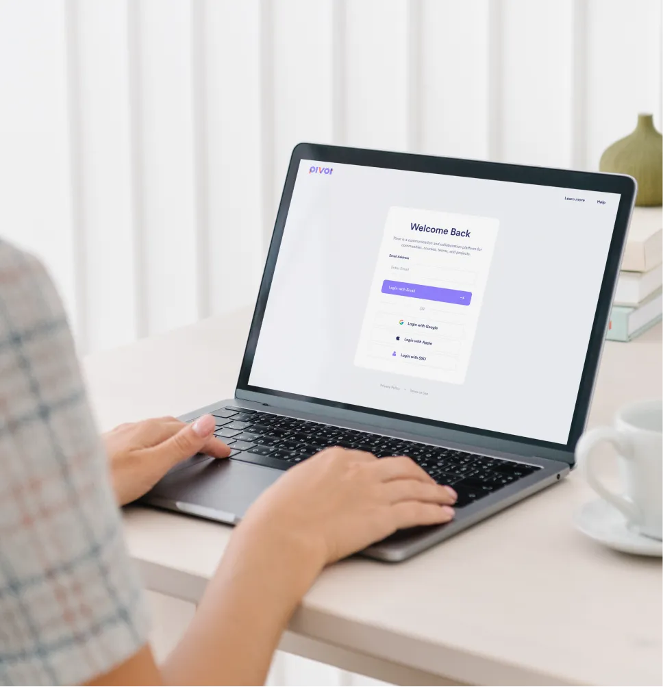 Person sitting at table in brightly light room with open laptop about to login to website.