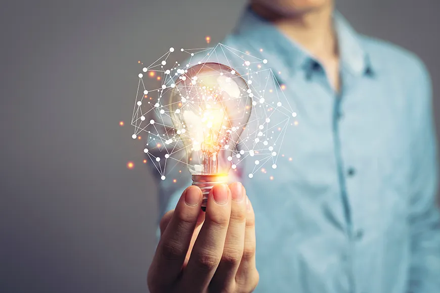 A man holds a lightbulb that is surrounded by a holographic web of interconnected points.