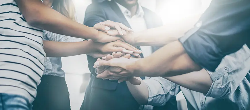 Close-up view of young business professionals putting hands together.