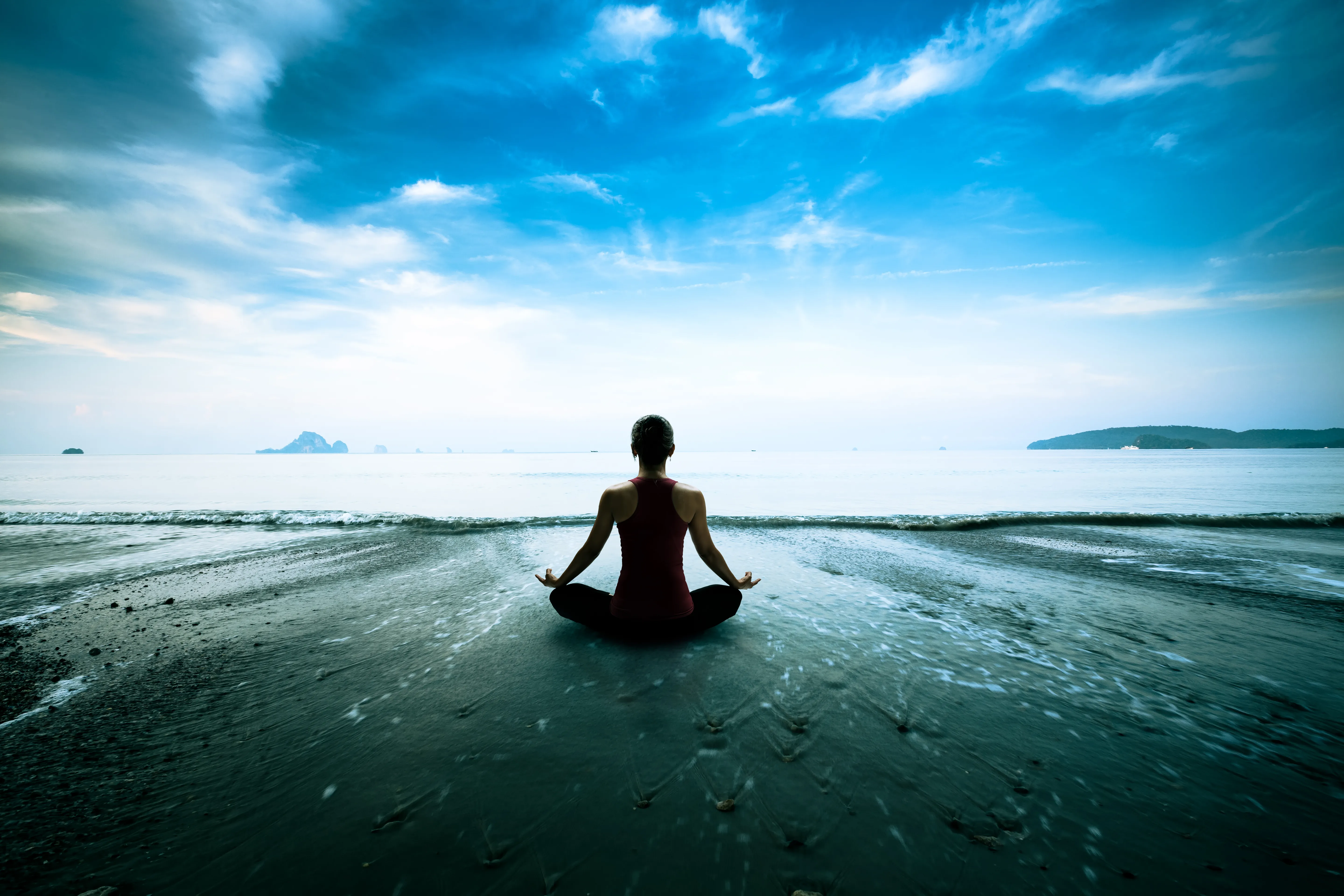 A woman meditating on a beach on a cloudy day.