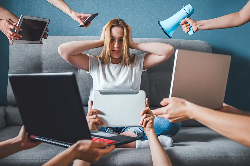 A woman sitting on a couch while multiple hands holding a telephone, tablets, and laptops are trying to get her attention.