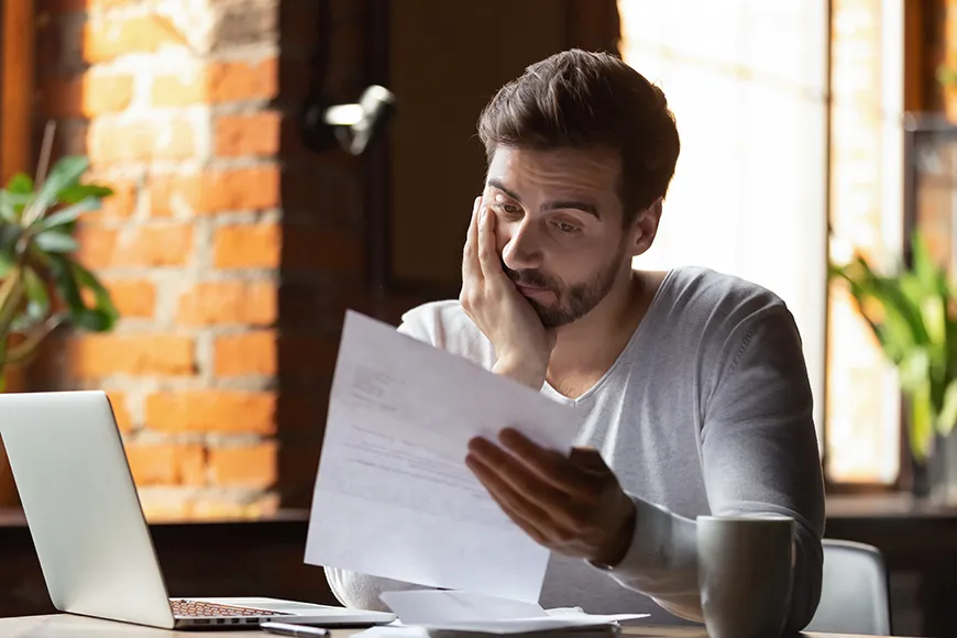 A man looks at a piece of paper, confused and frustrated
