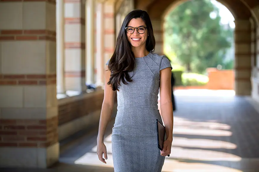 A young female student stands in an outdoor corridor at an institution of higher learning