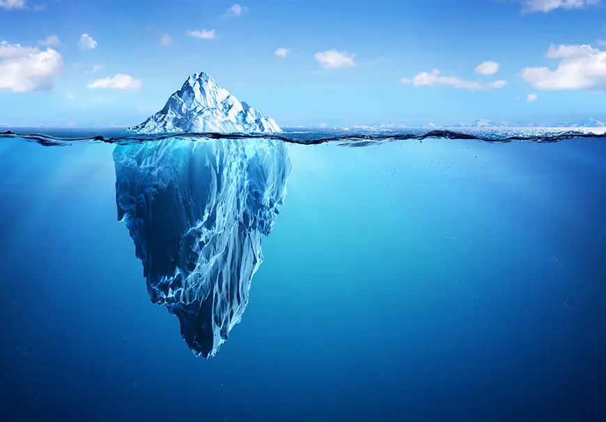 The tip of an iceberg peeking above the water, hinting at its larger hidden mass below the surface.