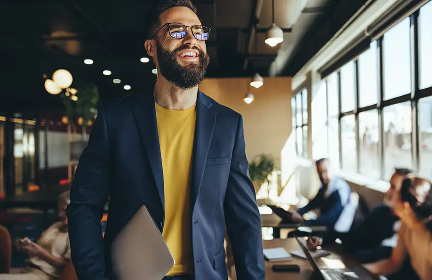 Happy young businessperson smiling while walking through a co-working space