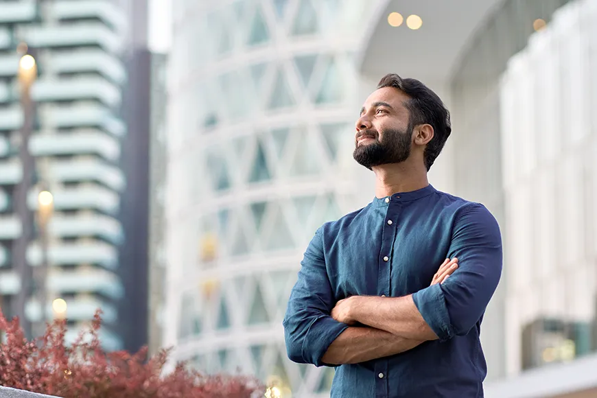 A confident man with crossed arms looks upward and smiles