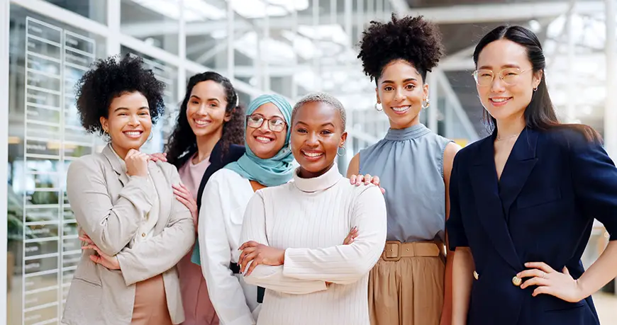 A diverse group of young women smile in an office setting