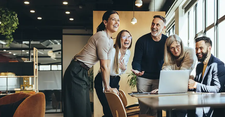 Happy business people laughing while collaborating on a new project in an office