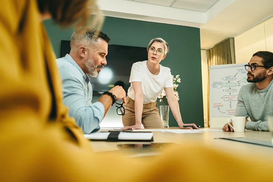 Woman with short hair leading a business meeting while others listen to her speak and inspire her team