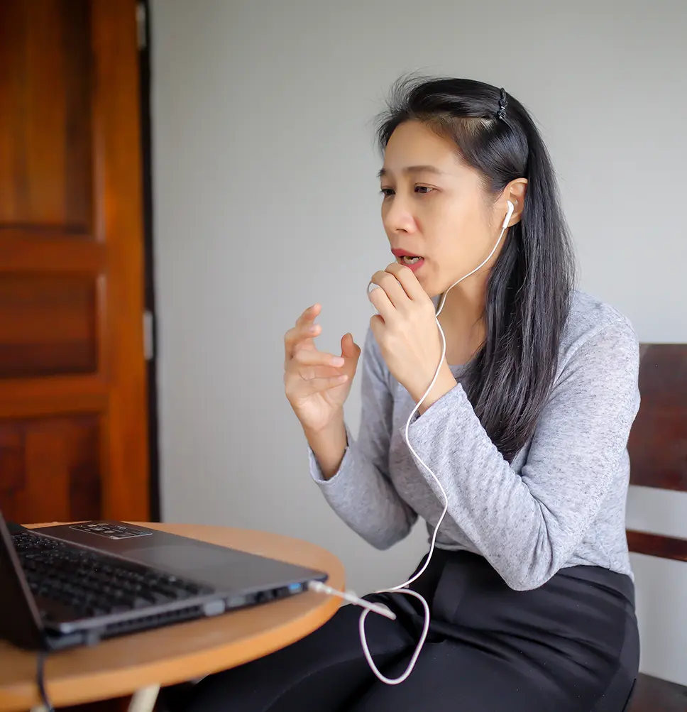 Person sitting at table talking during an online meeting.